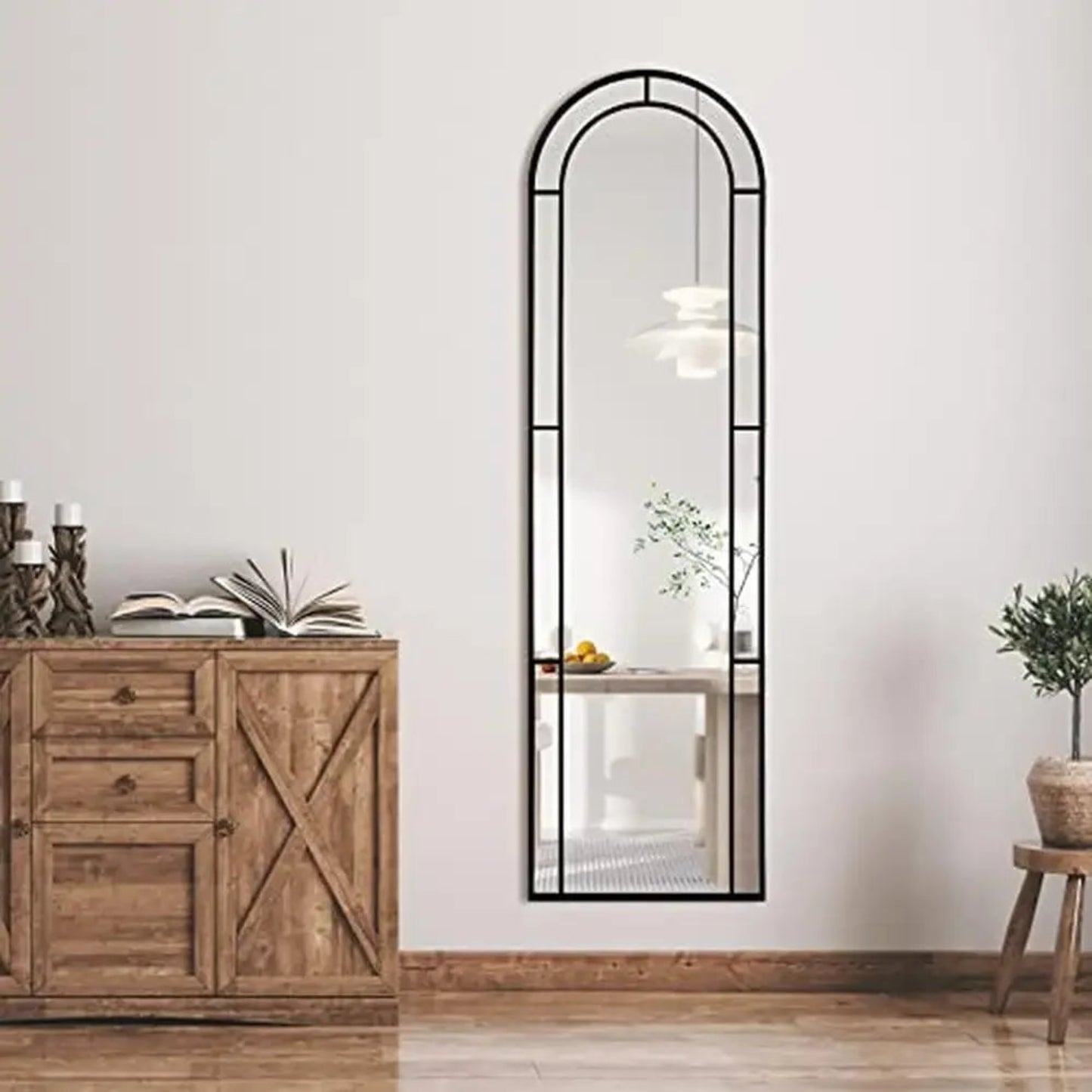 Full-length mirror with arched top in a room with wooden furniture and decor.