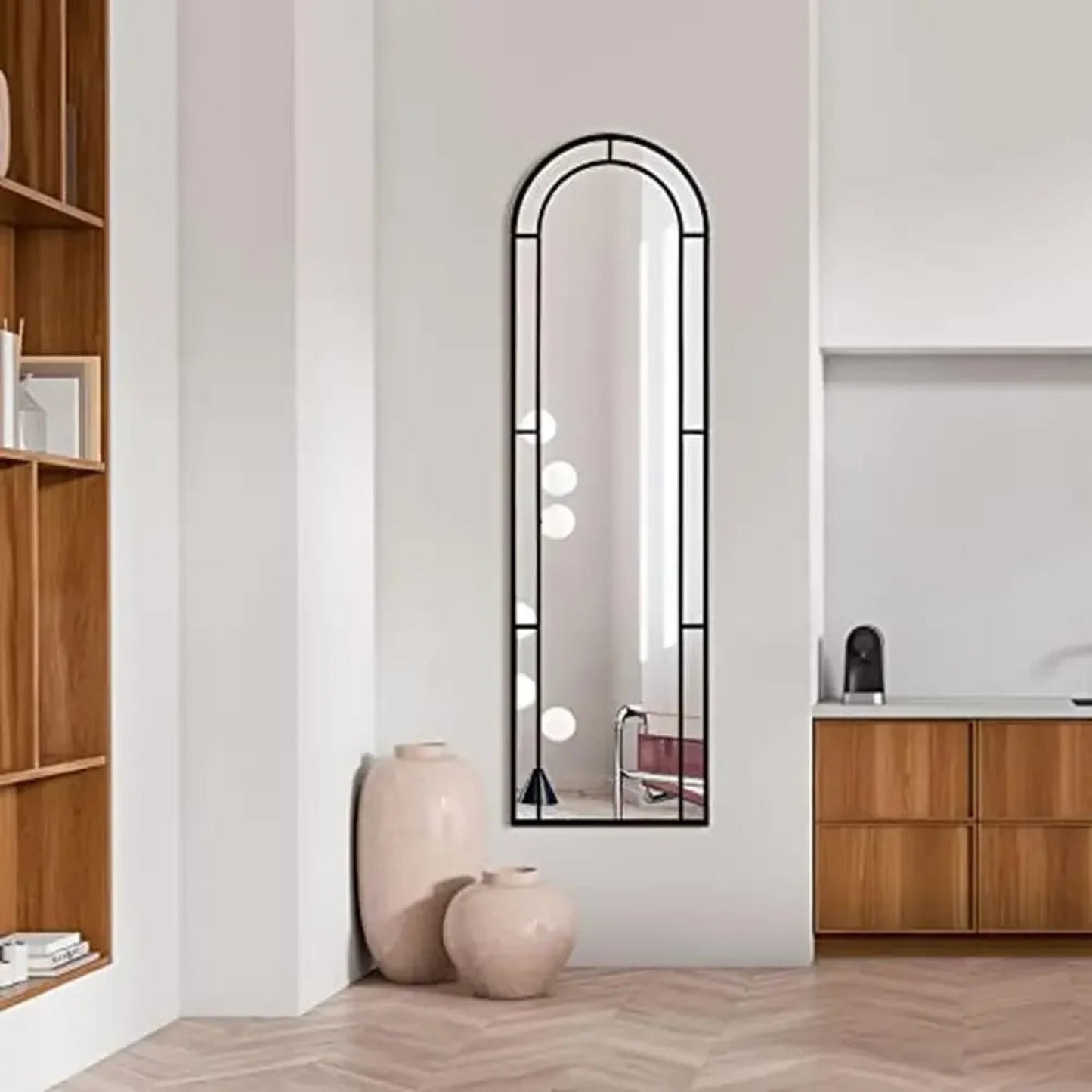 Long mirror with decorative frame on a wall in a room with wooden shelves and cabinets.