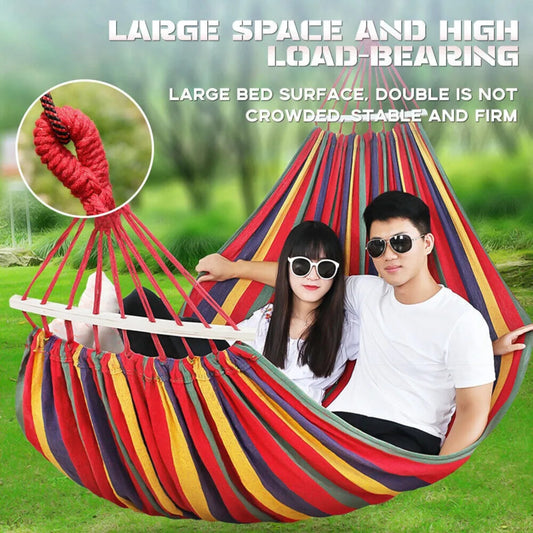 Colorful hammock with a couple sitting inside, surrounded by greenery.