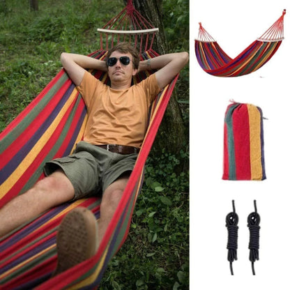 Man relaxing in a colorful hammock with additional hammock, straps, and ropes displayed.